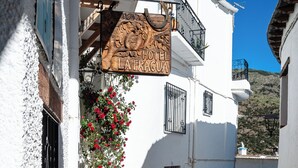 A narrow street with a white building featuring a wooden sign for 'Hotel La Faguas'. - Hotel La Fragua I (Trevelez)