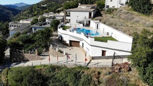 A hillside residential area with modern houses, a swimming pool, and a stone pathway. - Hotel La Fragua I (Trevelez)