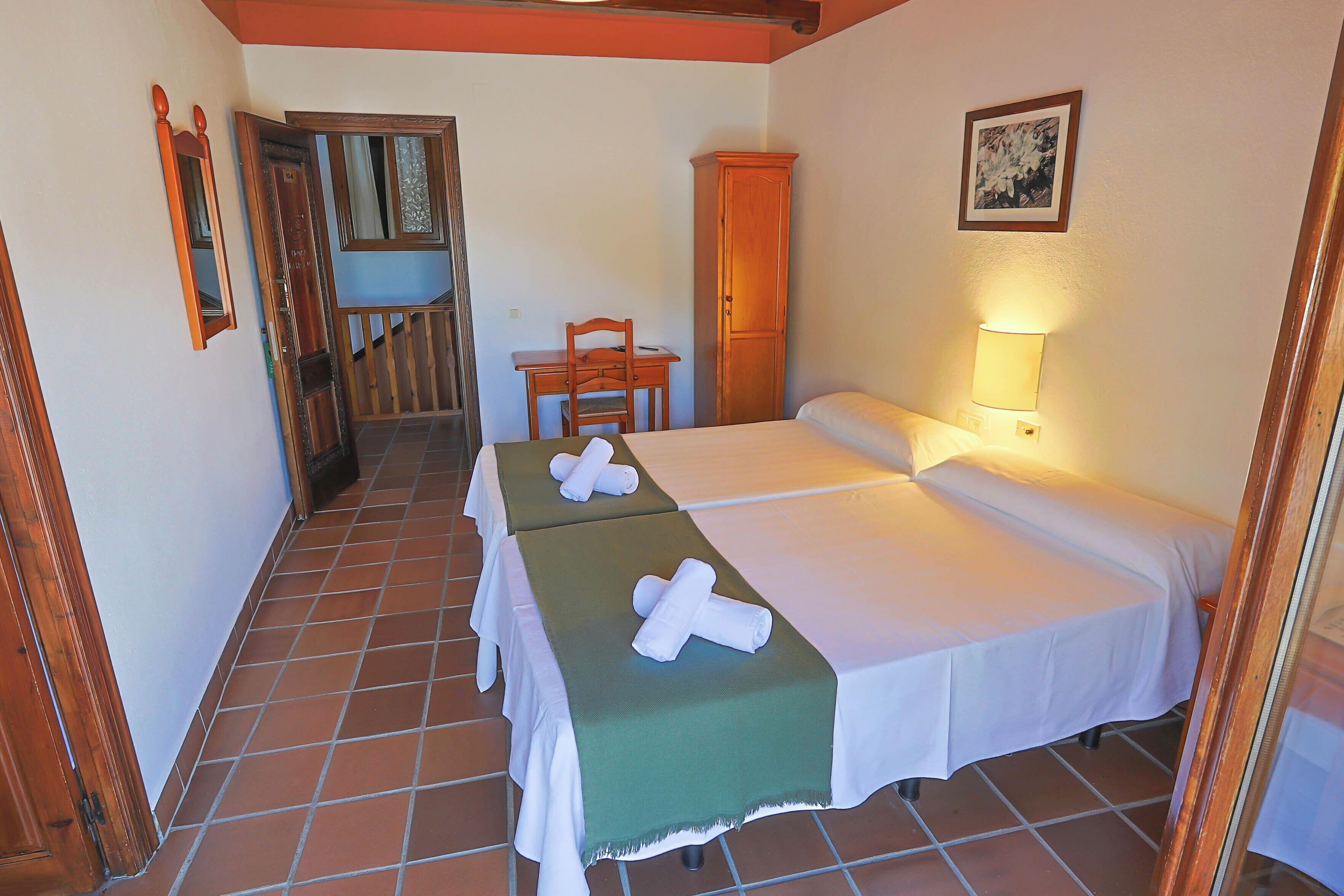 Una habitación de hotel con dos camas, un escritorio, una silla y un armario.