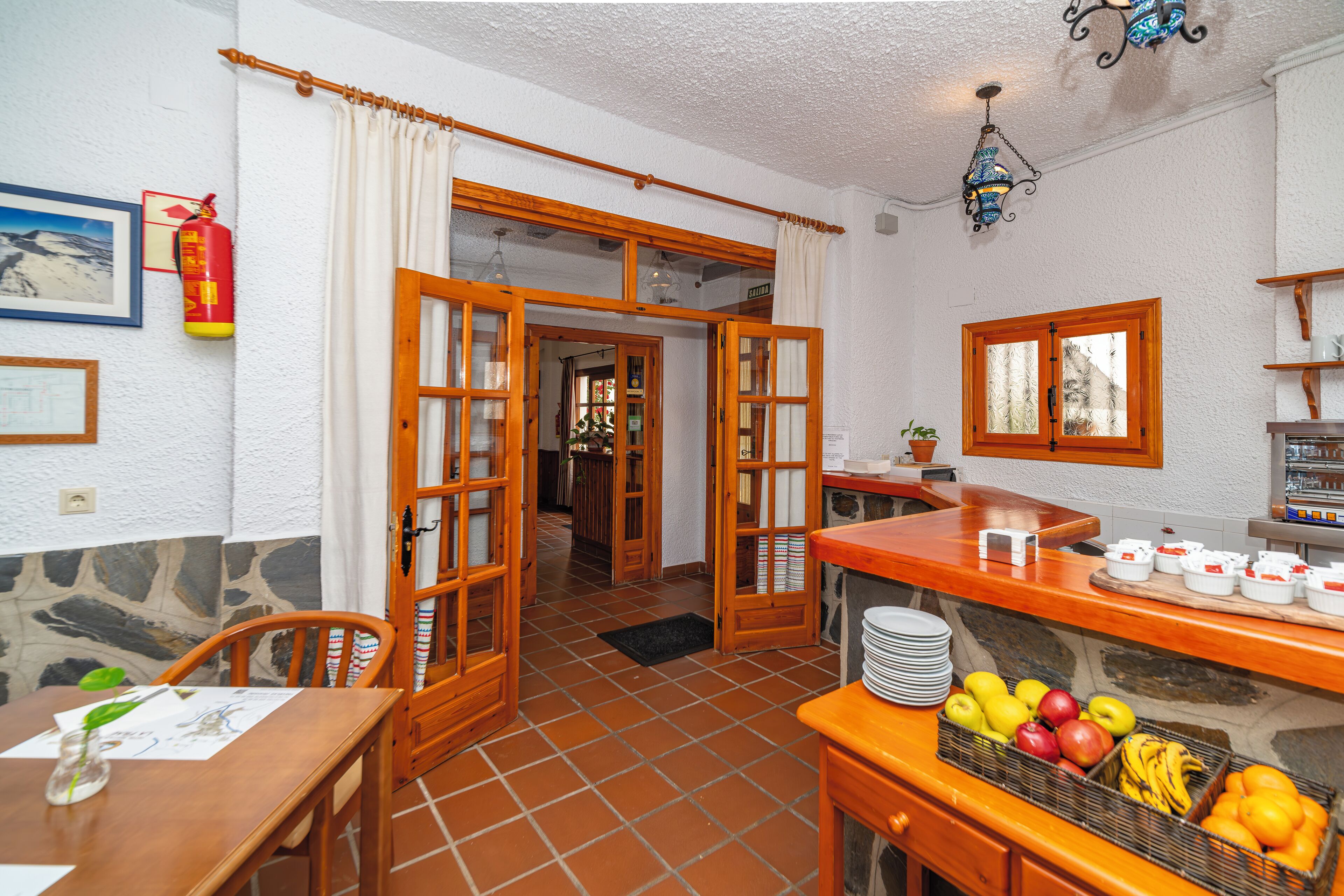 Une cuisine avec un mur en pierre, des portes en bois et un panier de fruits posé sur le comptoir.