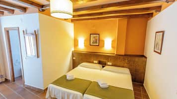 Une chambre d’hôtel avec deux lits, un plafond en bois et un luminaire fixé au mur.