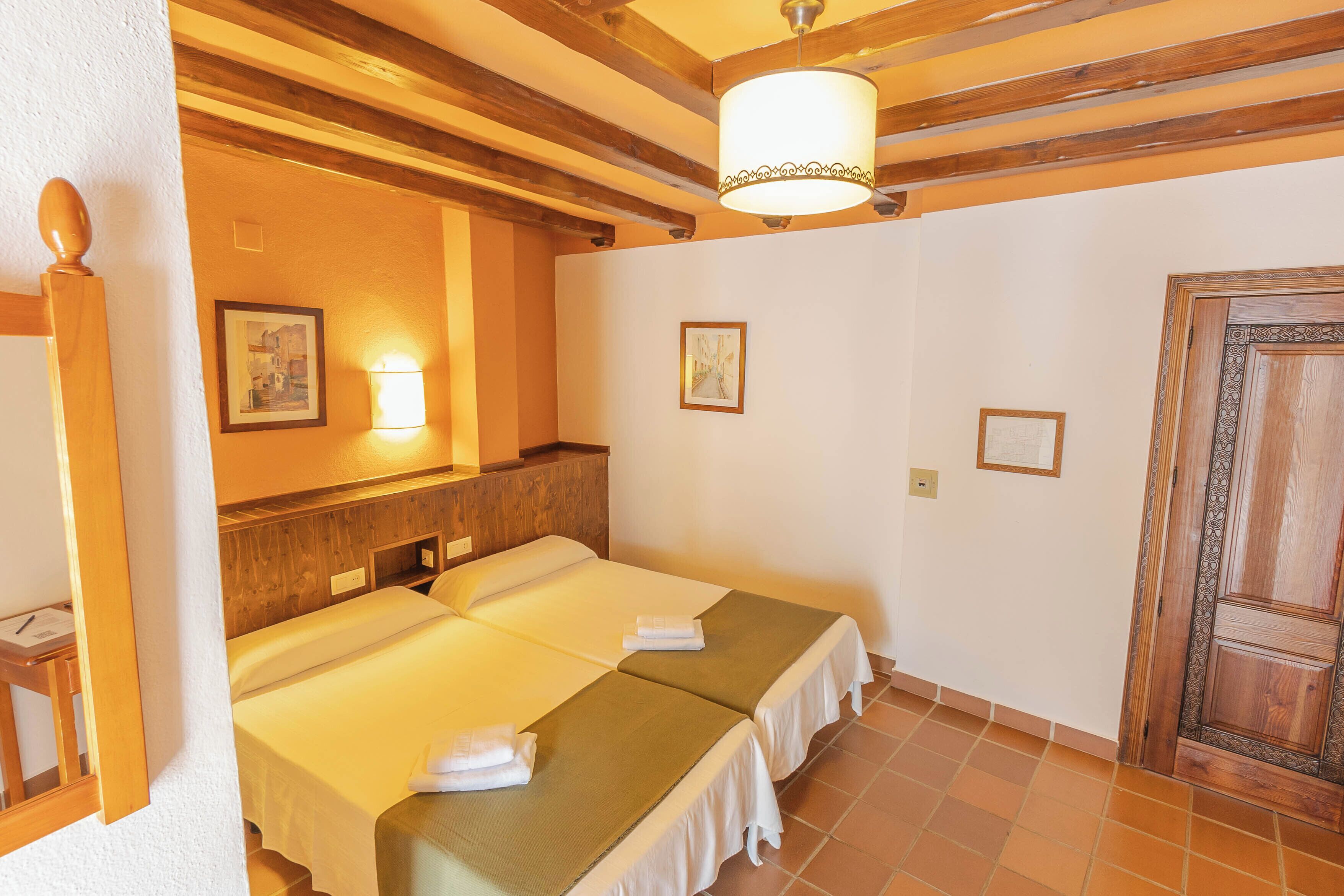 A hotel room with two beds, wooden beams, a large mirror, and a wooden door.