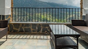 A balcony with stone walls, wooden beams, and wicker furniture. - Hotel La Fragua II (Trevelez)