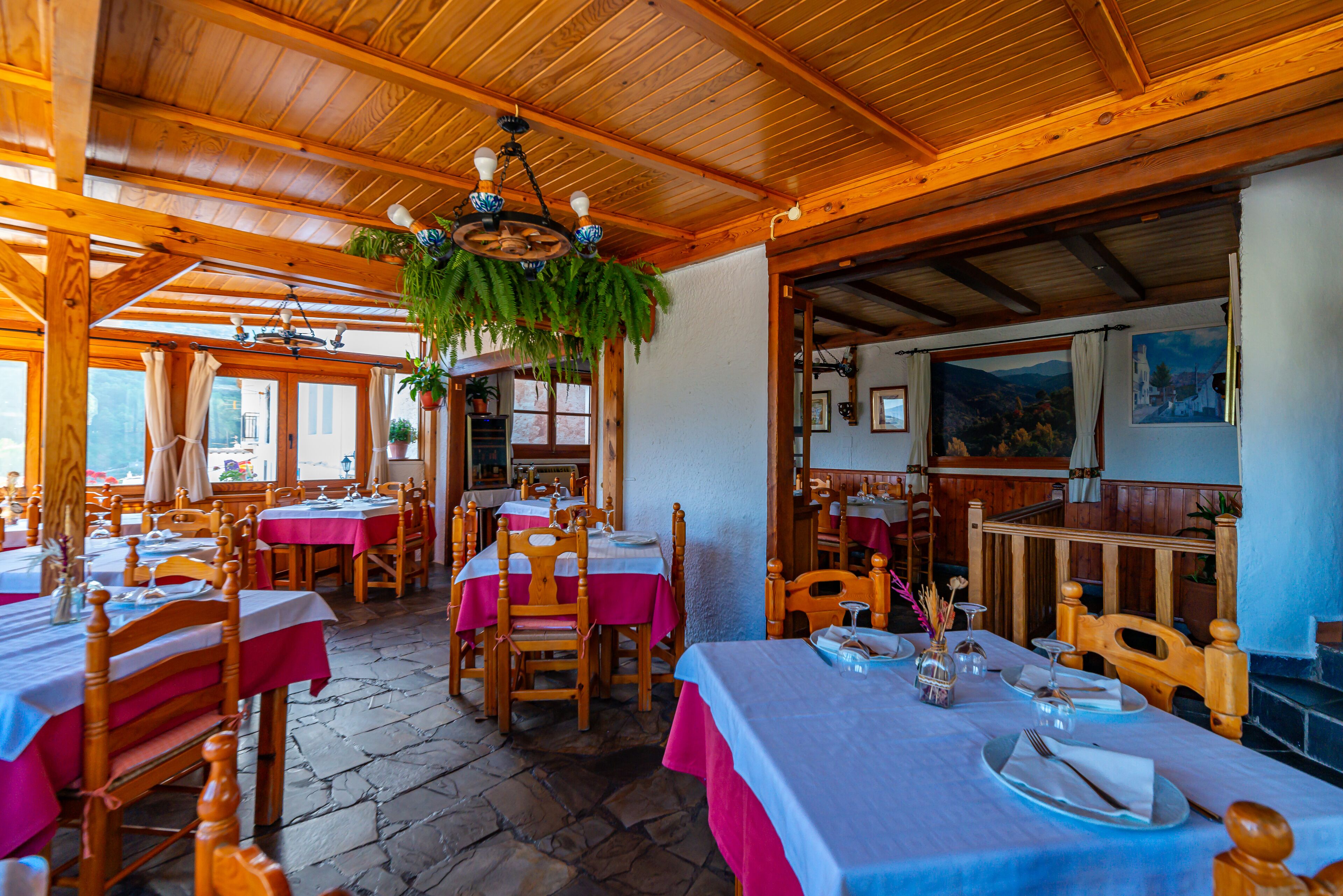 En restaurant med træpaneler, stengulv og dækkede borde.