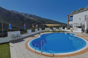Una piscina al aire libre de temporada, sombrillas, tumbonas