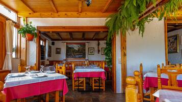 A restaurant with wooden tables and chairs, a stone floor, and a rustic interior.