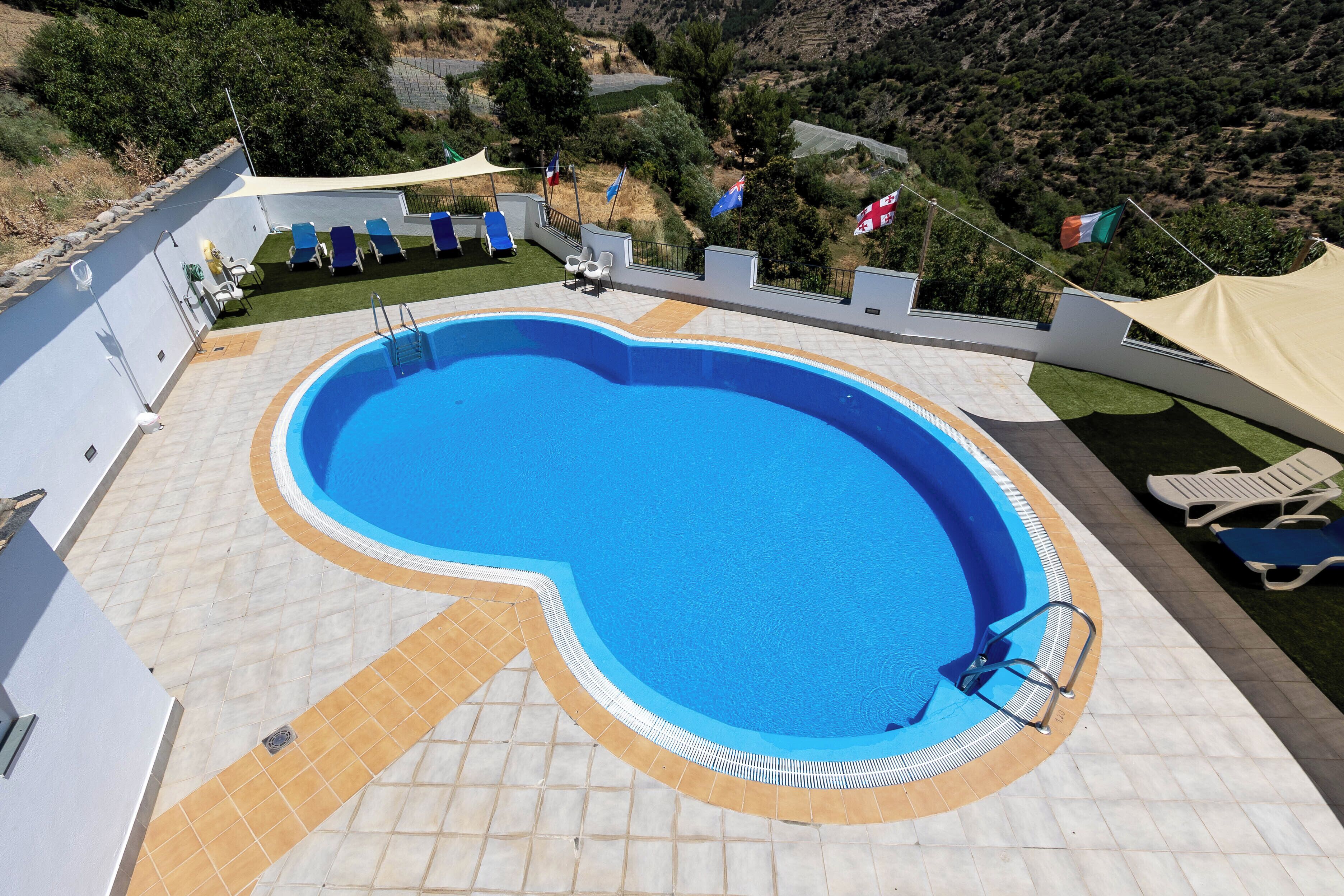 Una piscina al aire libre de temporada, sombrillas, tumbonas