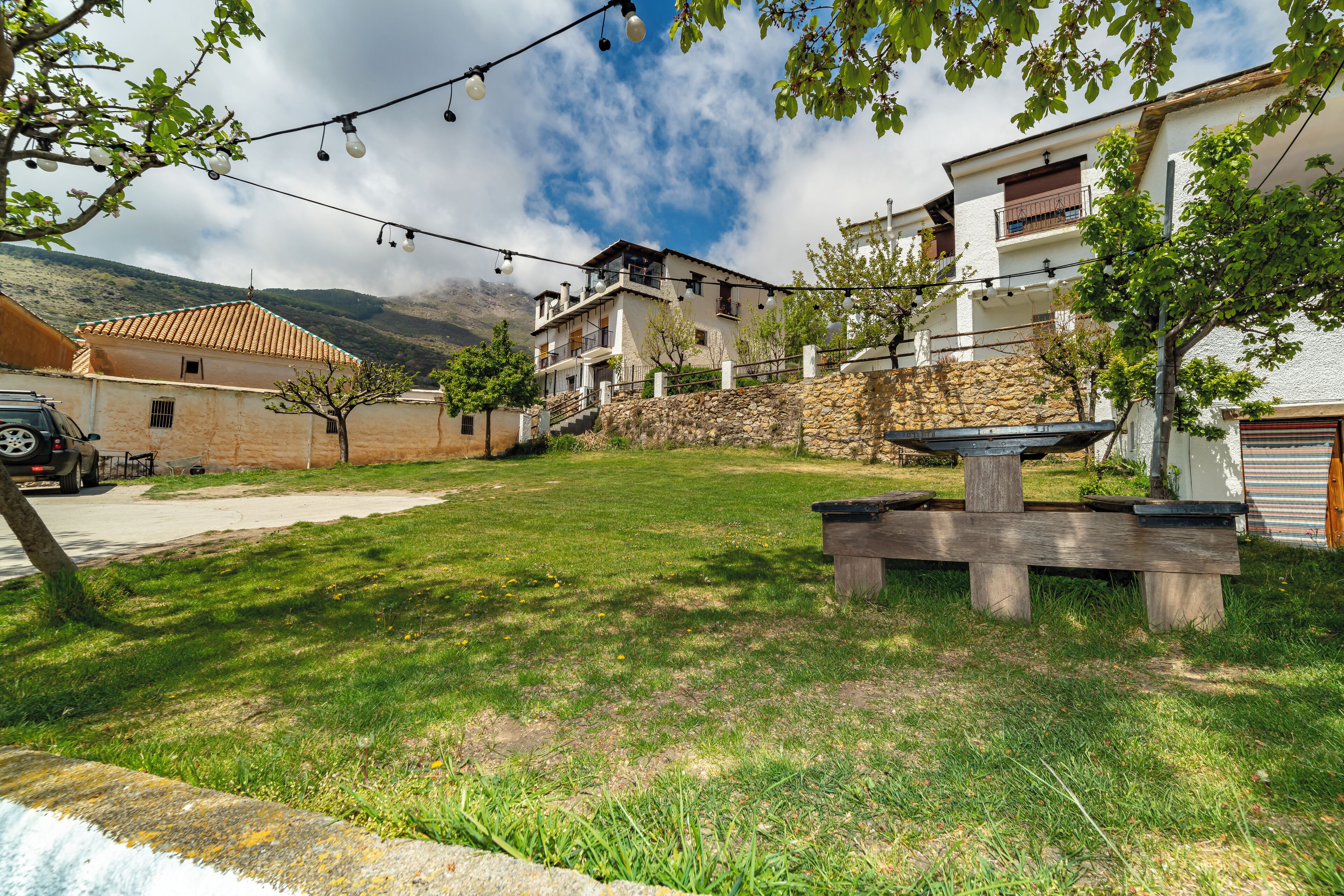 A residential area with a grassy yard, stone walls, and a wooden bench.