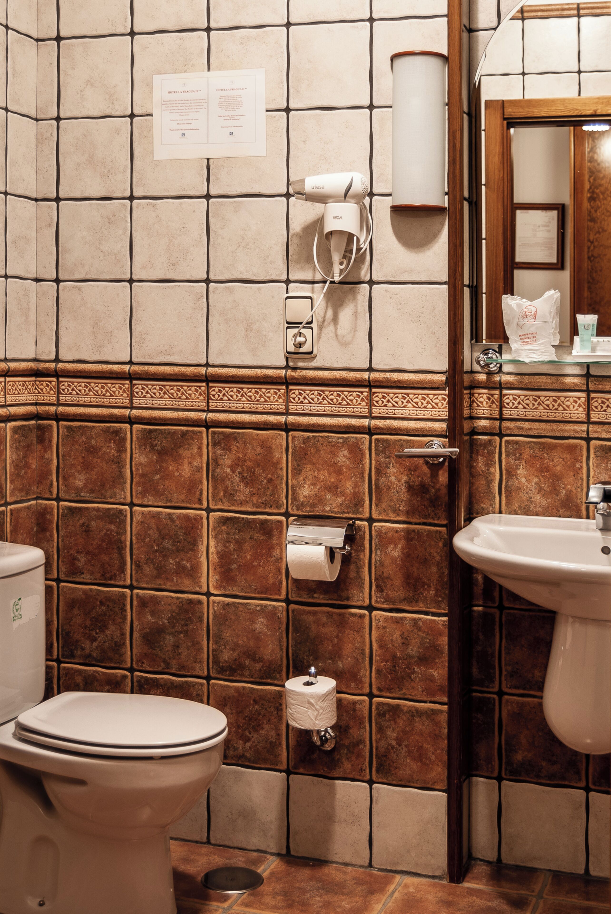 Een badkamer met toilet, wastafel en handdoekdispenser.