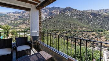 A balcony with wicker furniture and a view of a mountainous landscape.