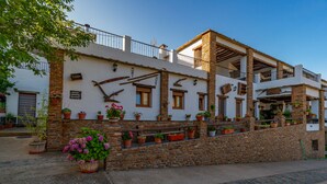 A traditional building with stone walls, multiple balconies, and potted plants. - Hotel La Fragua II (Trevelez)