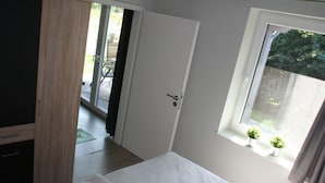 Un dormitorio con cama, una puerta que da a un balcón y una ventana con cortinas.