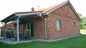 Una casa de ladrillo con un porche cubierto, una antena parabólica y un ventanal pequeño.