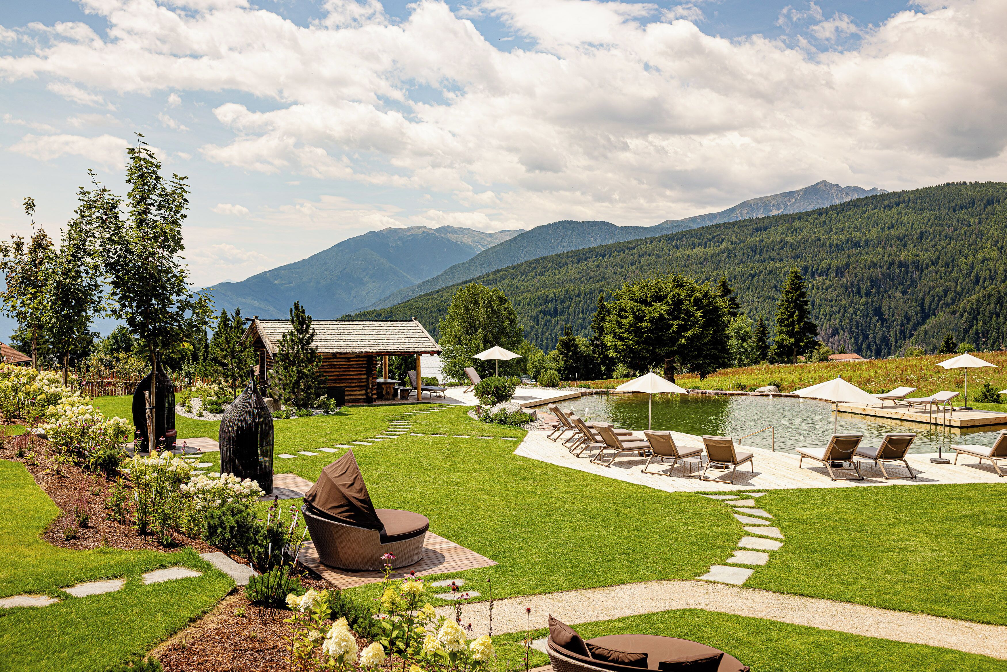 Un espace extérieur aménagé avec une piscine, des chaises longues et une vue sur les montagnes.
