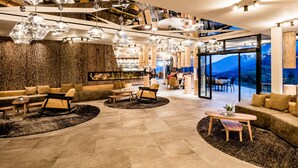 Un interior moderno con una zona de bar, arreglos de asientos y vistas a montañas a través de amplios ventanales.