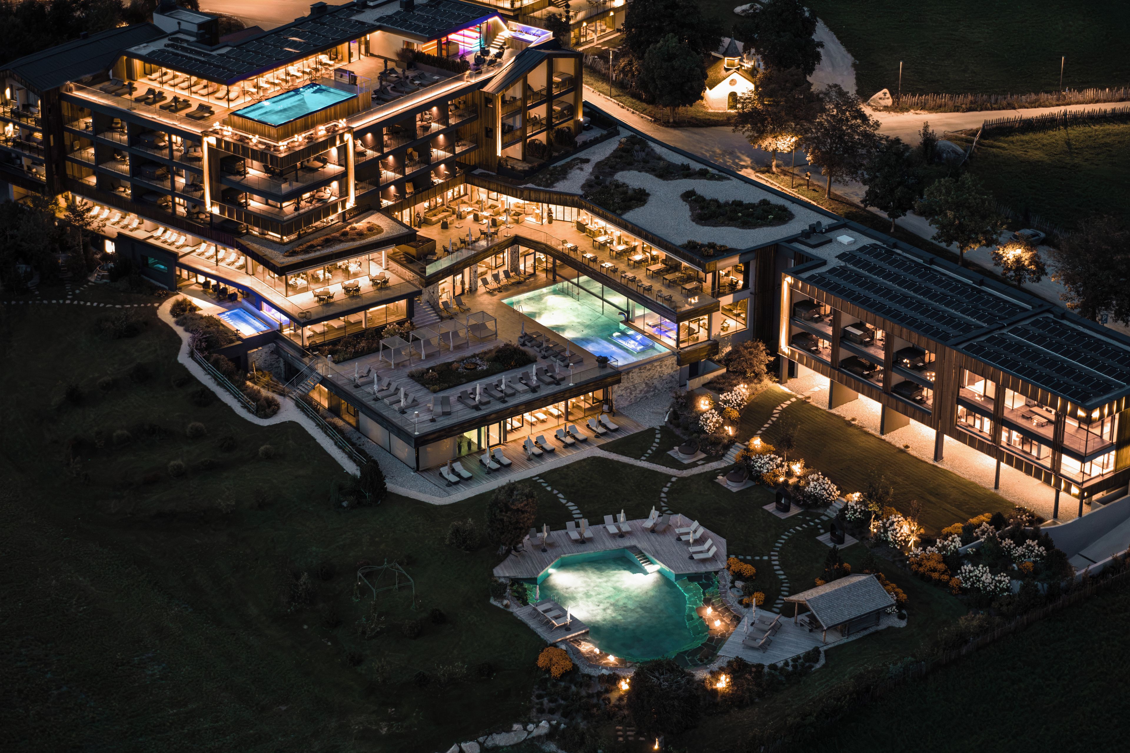 Ein mehrstöckiges Hotel mit Pool, Außenbereich und einer gut beleuchteten Landschaft.