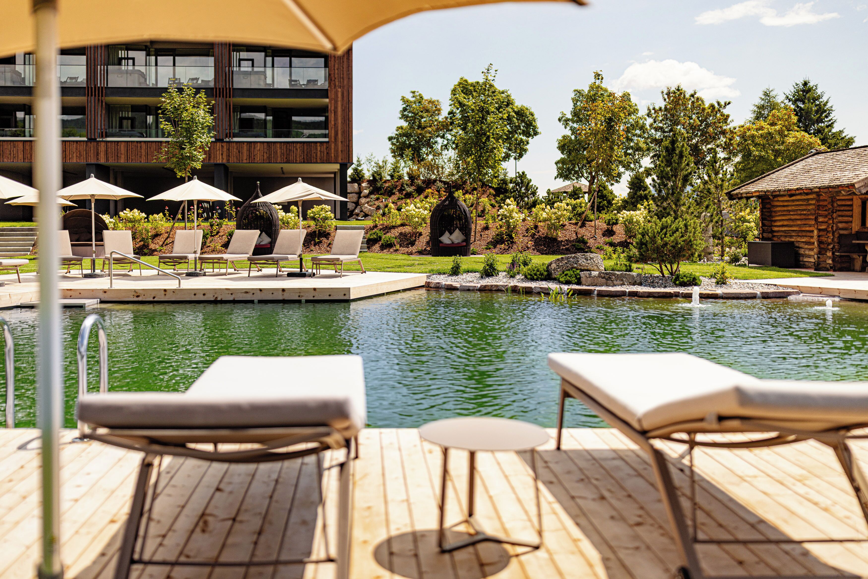 Un espace aménagé au bord de la piscine, avec des chaises longues, des parasols et une terrasse en bois.