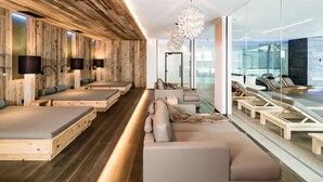 Un spa moderno con paredes de madera, varias zonas de estar y un amplio ventanal con vistas.