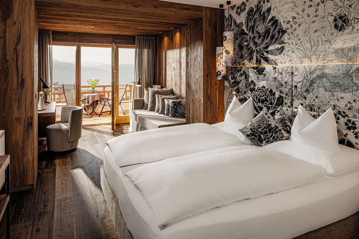 A bedroom with a large bed, a desk, and a view of the mountains.