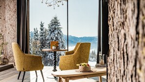 Una habitación acogedora con un ventanal grande, dos sillones, una mesita y un árbol de Navidad.