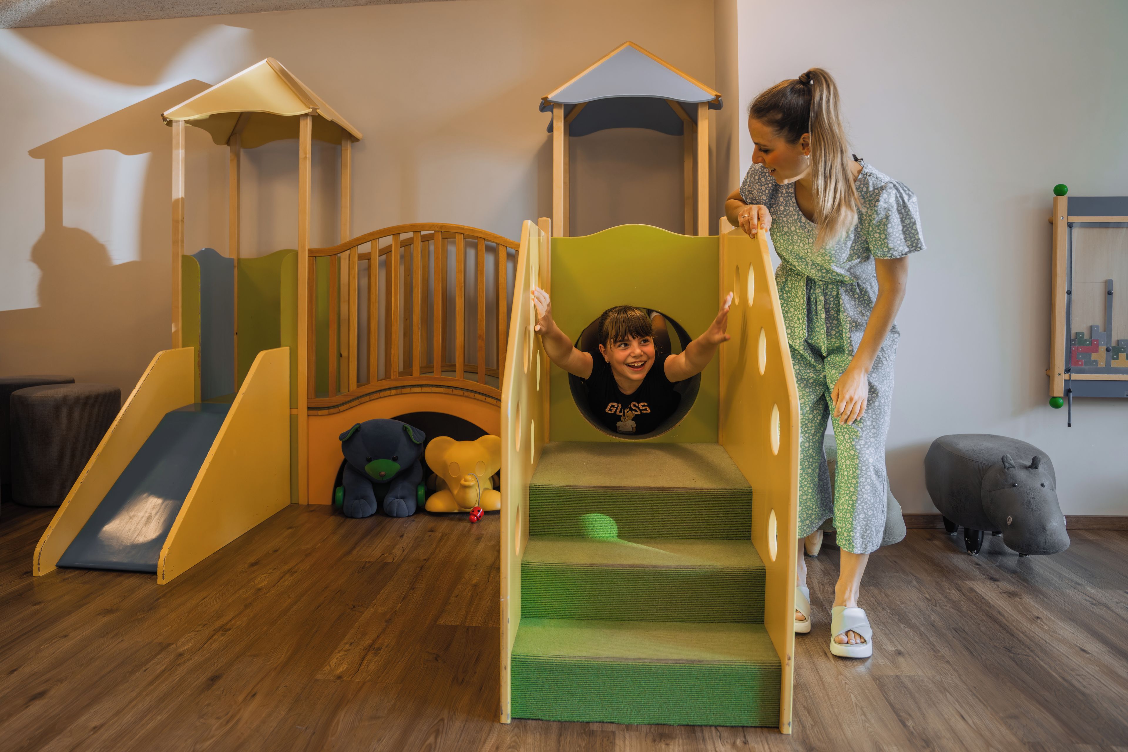 A play area with a slide, climbing steps, and a small bridge.
