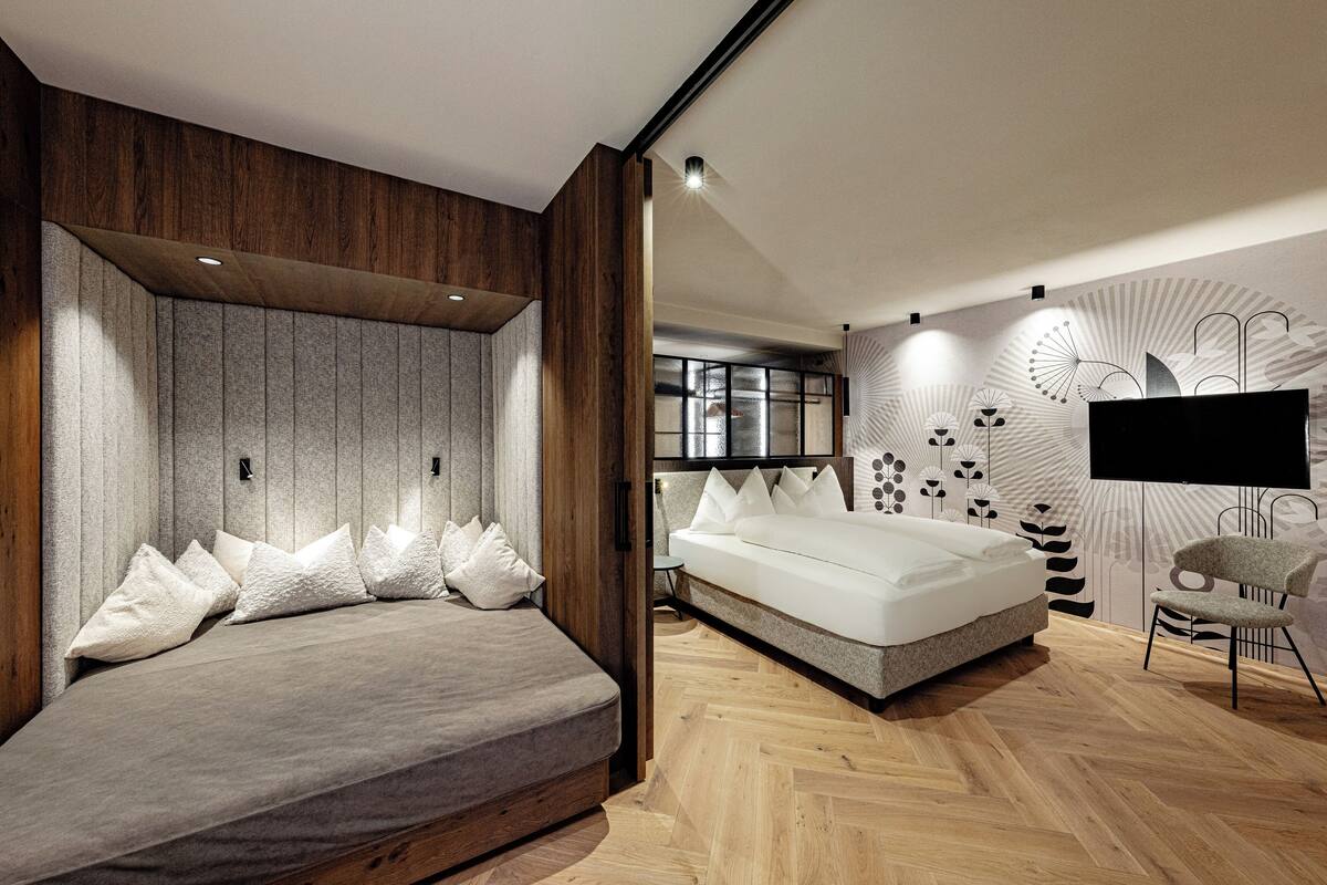 A modern bedroom with a bed, a chair, and a TV.