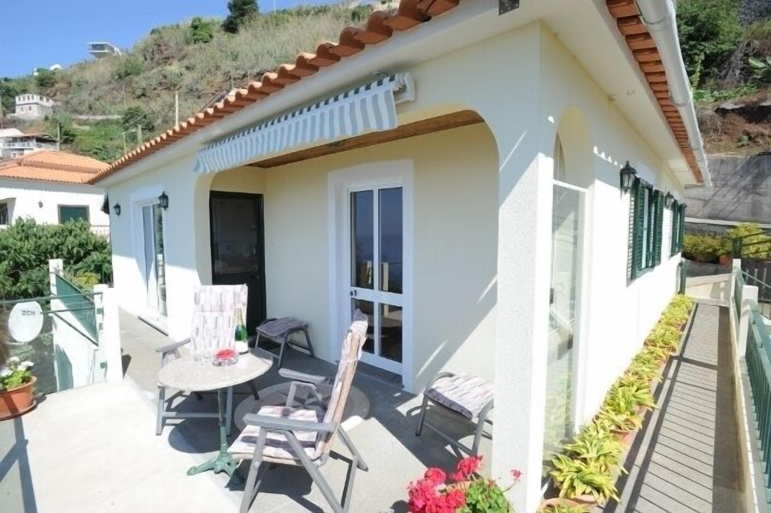 A small house with a patio, a round table, and two chairs.