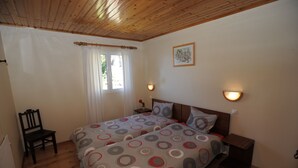 A bedroom with two beds, wooden flooring, a chair, a window with curtains, and wall-mounted lights. - 60 sqm apartment with 2 bedrooms and fantastic sea views (Arco da Calheta)