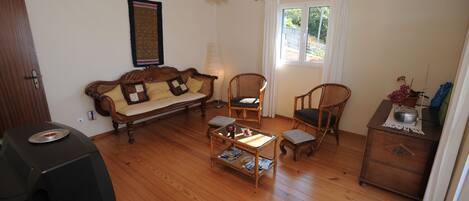 A living room with a sofa, two chairs, a coffee table, and a TV.