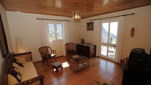 A cozy living room with a wooden ceiling, a sofa, two chairs, a coffee table, and a fireplace. - 60 sqm apartment with 2 bedrooms and fantastic sea views (Arco da Calheta)