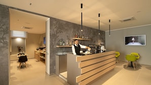 Un moderno vestíbulo de hotel con una recepción, una zona de bar y un área de descanso con sillones.