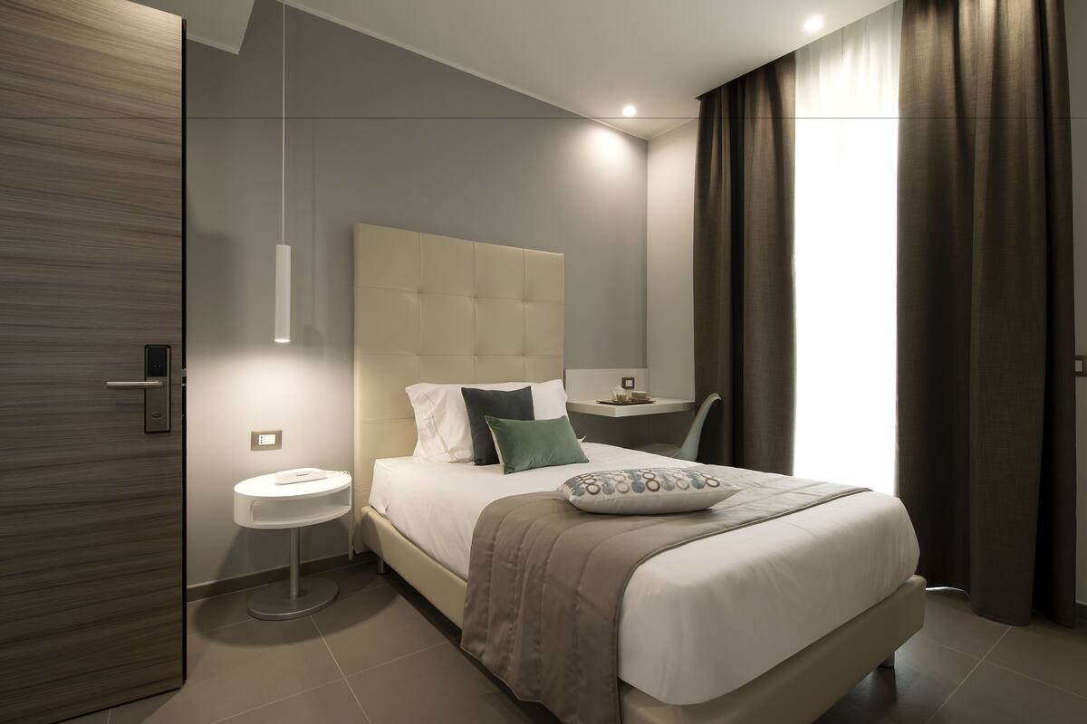 Un dormitorio moderno con una cama grande, una mesita de noche y una mesita auxiliar redonda.