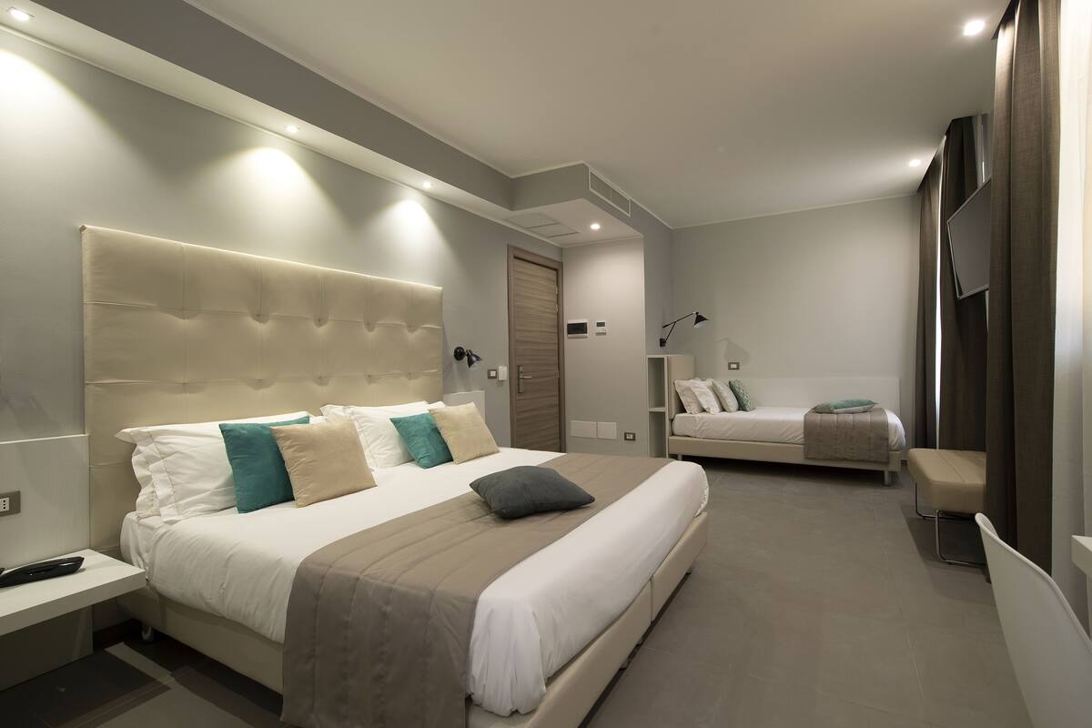 Un dormitorio moderno con una cama grande, un sofá cama más pequeño y un escritorio.