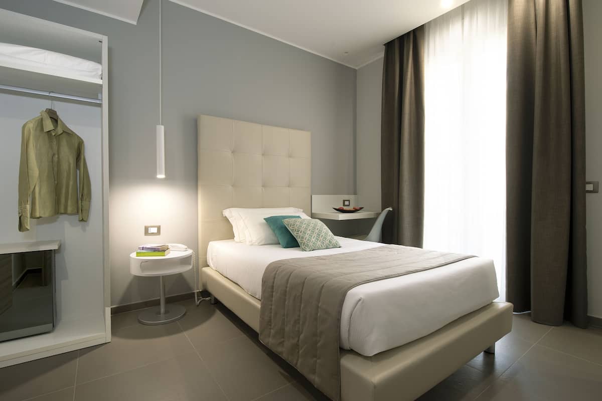 Un dormitorio moderno con una cama grande, una mesita de noche y un perchero.