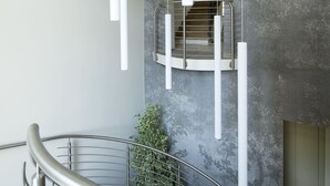 Un interior moderno con una escalera curva, una pared gris con textura y un diseño minimalista.