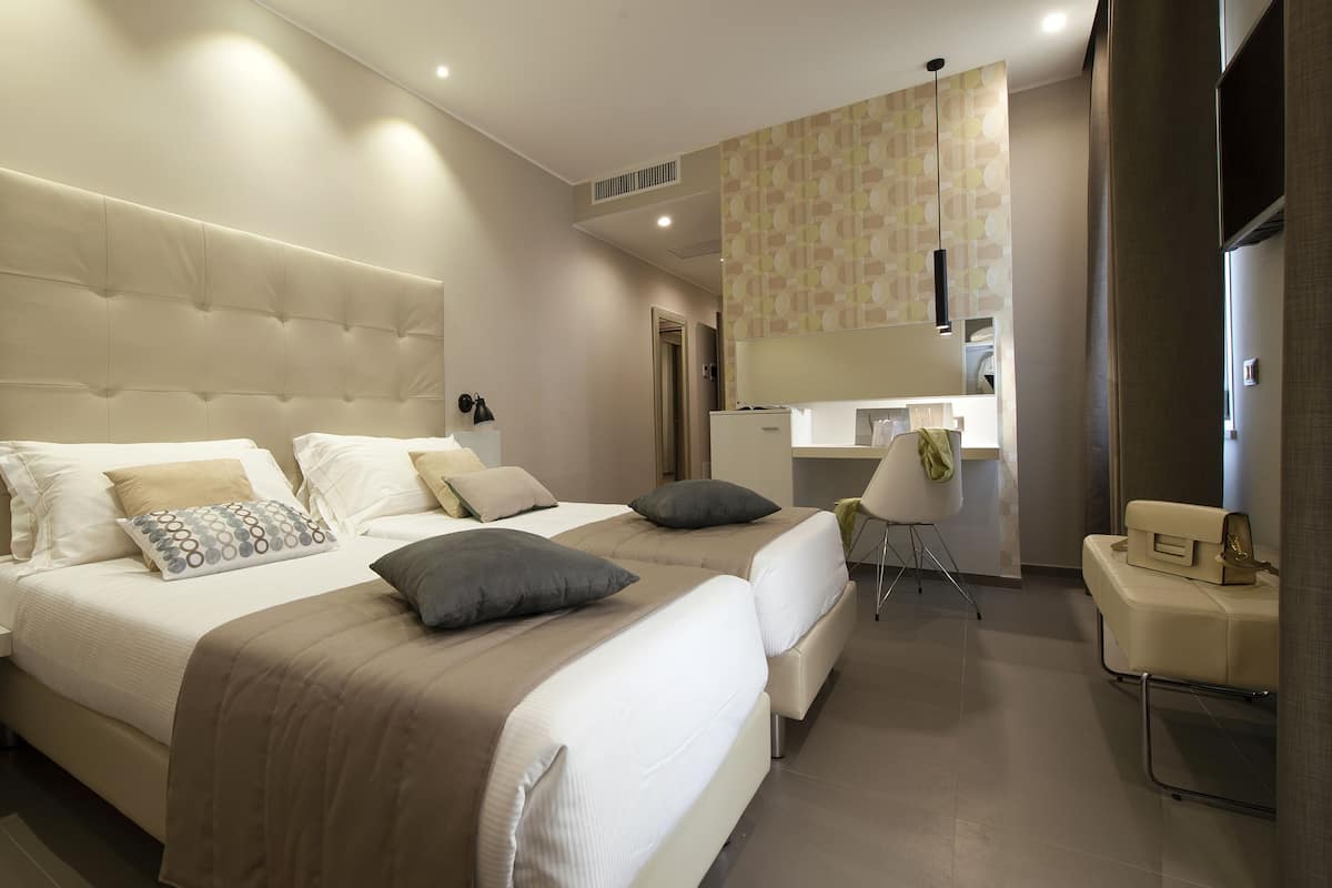 Una habitación de hotel moderna con una cama grande, mesitas de noche, un escritorio y una silla.