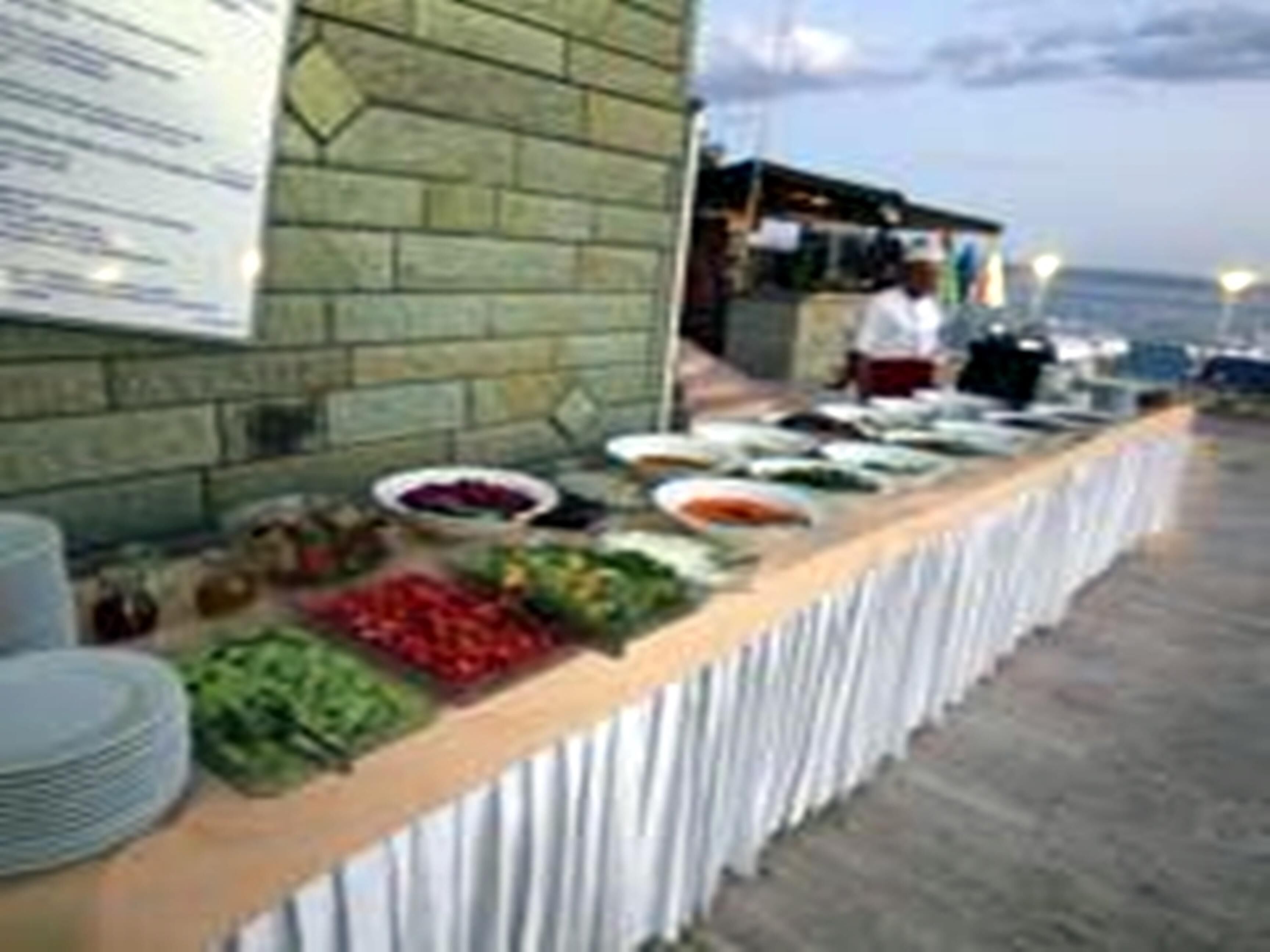 A buffet setup with various food items and a menu board on a brick wall.