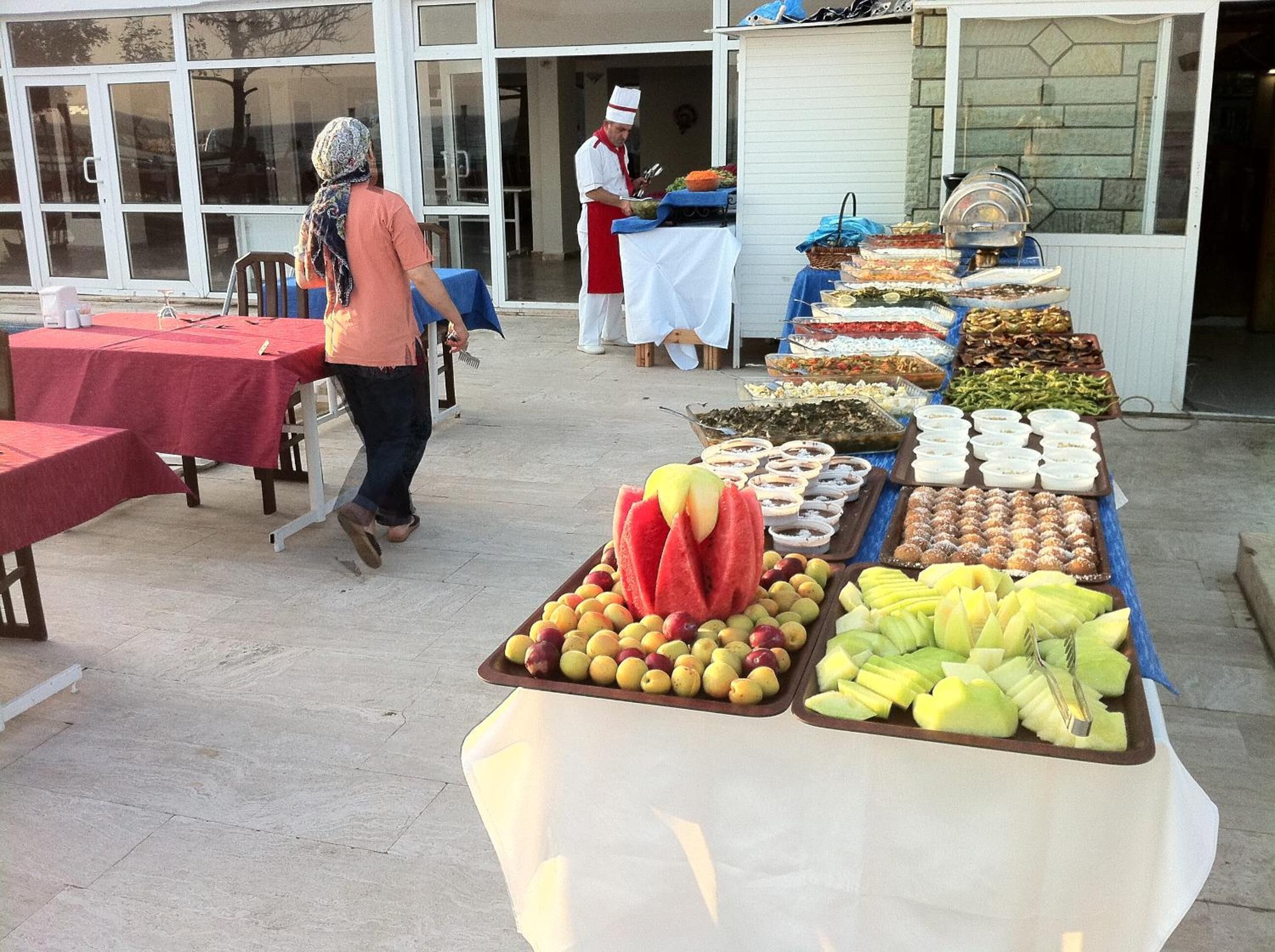 An outdoor buffet with various fruits and dishes displayed on tables.