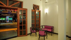 Una habitación con una puerta de madera, un sofá rosa y dos sillas.
