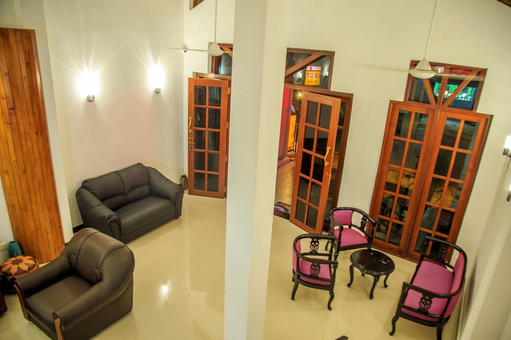 A living room with a sofa and chairs, wooden doors, and a view of the outside.