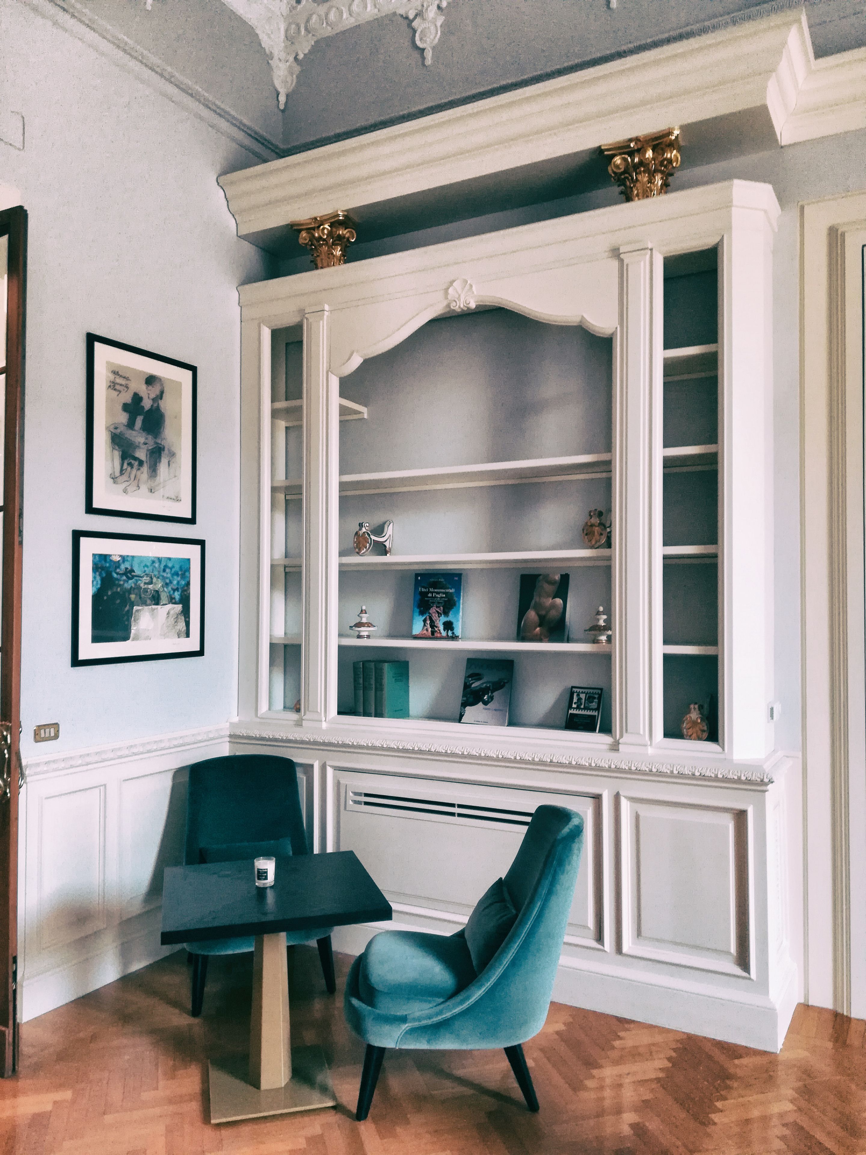 Una stanza con una libreria a muro, un tavolo da pranzo con due sedie e opere d'arte incorniciate appese alla parete.