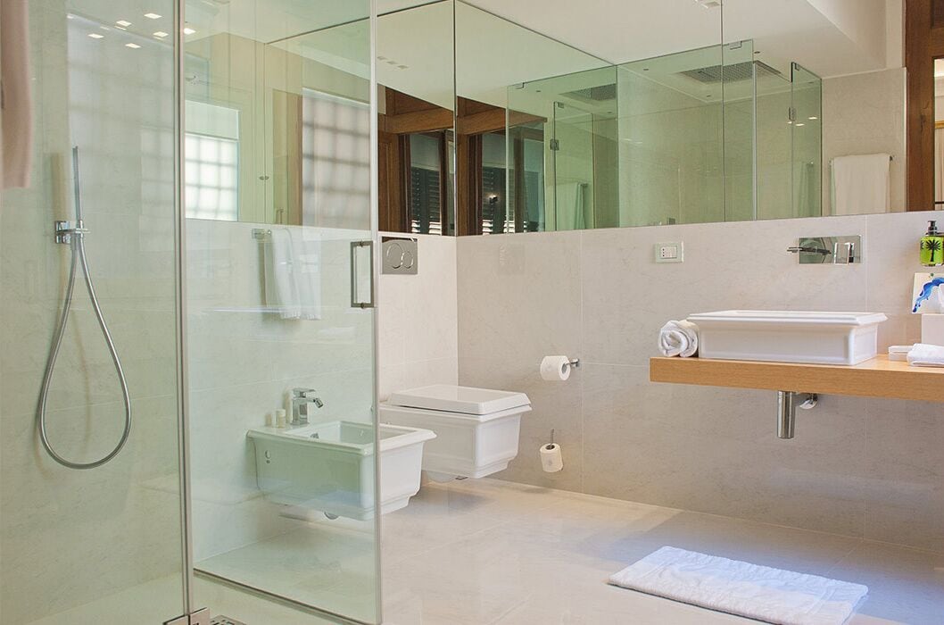 Ein modernes Badezimmer mit Duschkabine aus Glas, einer weißen Toilette und einem Waschtisch mit Spiegel.