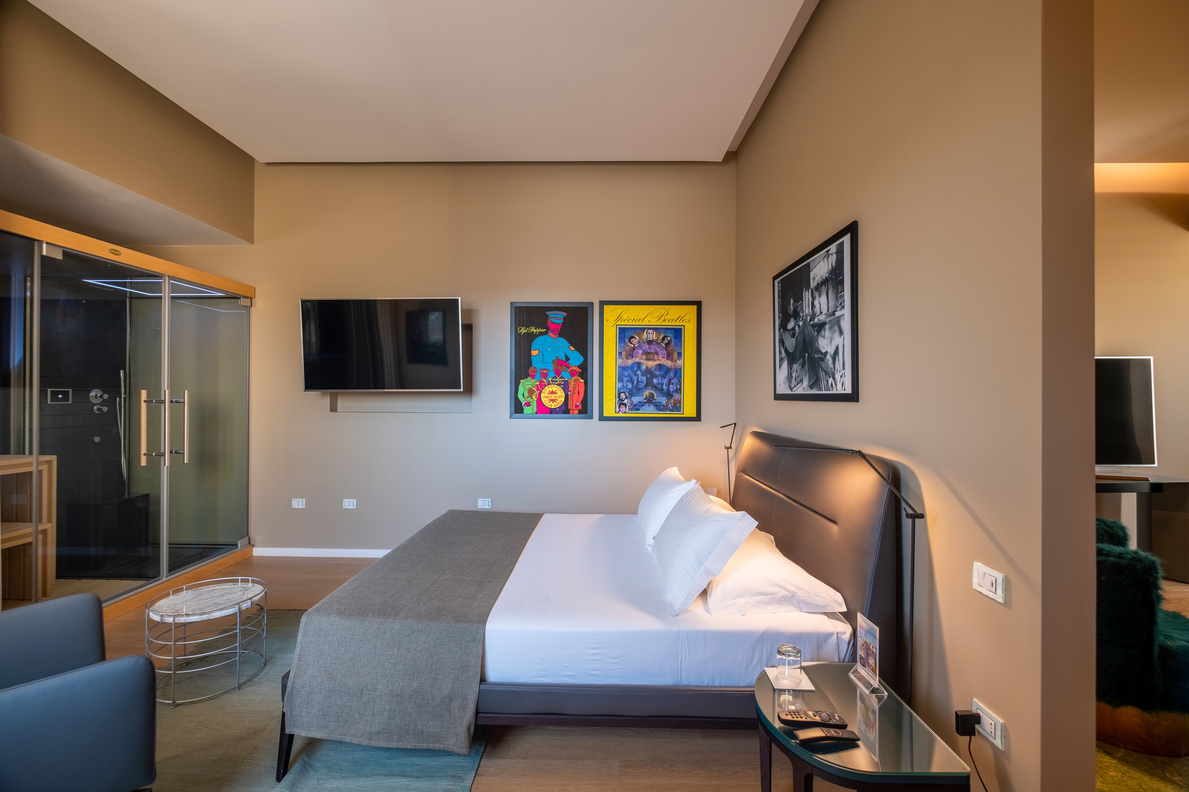 Una habitación de hotel moderna con cama, mesita de noche y cabina de ducha de vidrio.