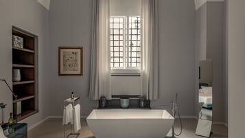 Ein modernes Badezimmer mit einer freistehenden Badewanne, einem Waschtisch mit Spiegel und einem Fenster mit Vorhängen.