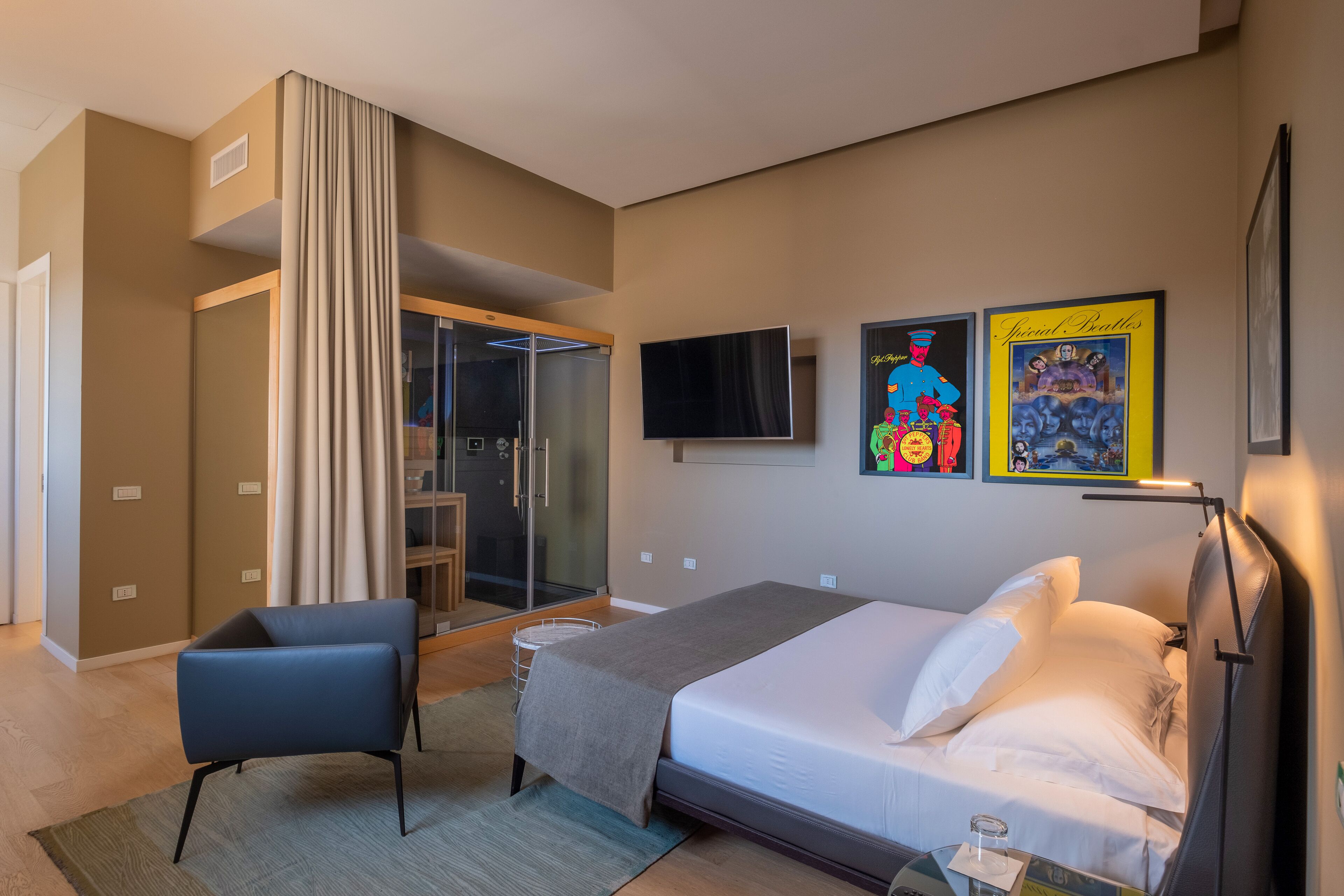 A hotel room with a bed, a chair, a TV, and a shower area.