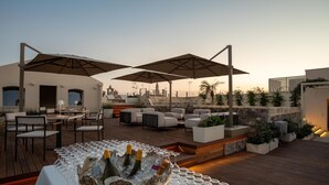 Una terraza en la azotea con asientos al aire libre, zona de bar y vistas del horizonte urbano.