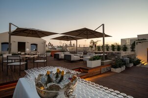 Una terraza en la azotea con asientos al aire libre, zona de bar y vistas del horizonte urbano.