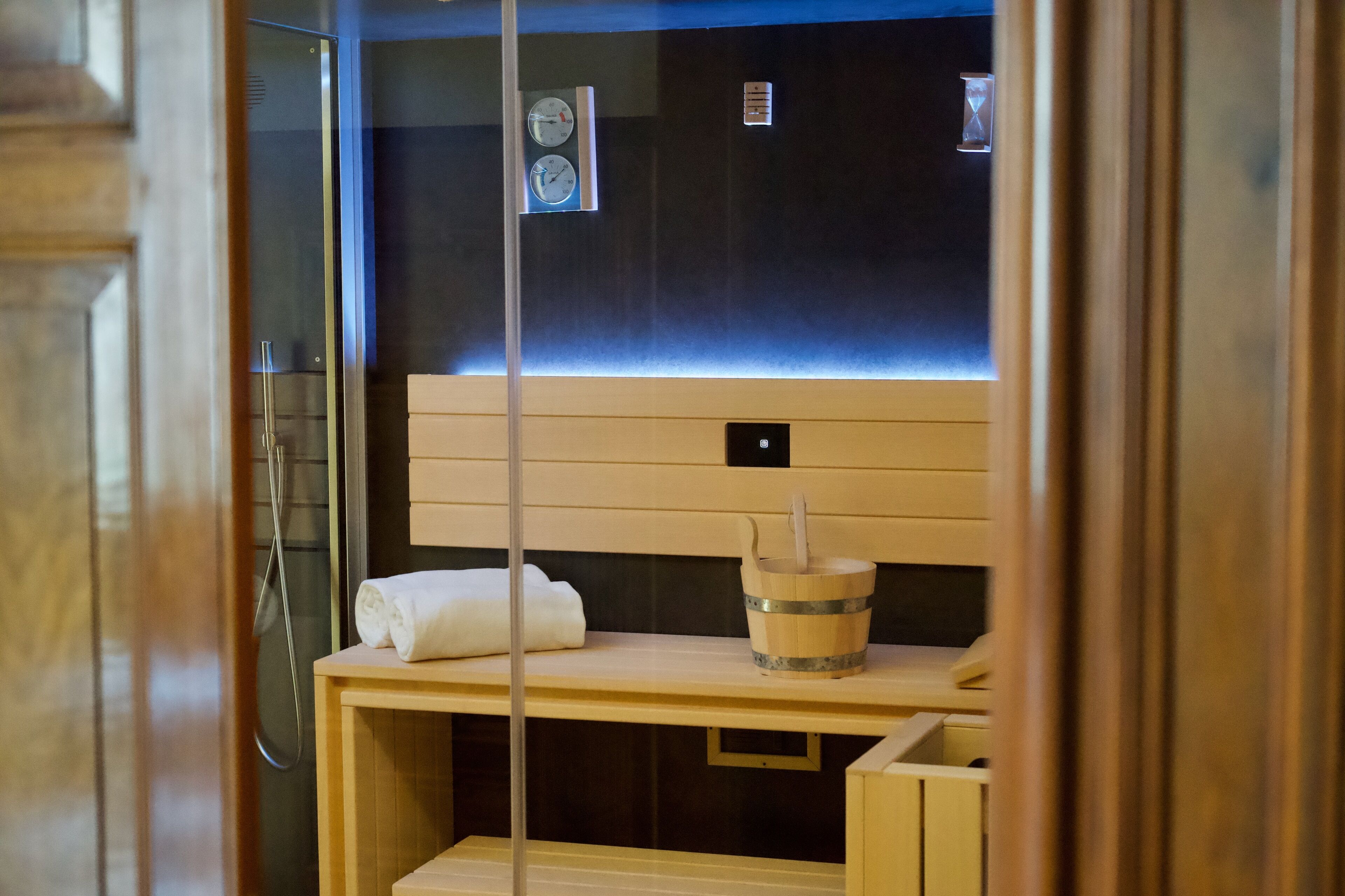A sauna with a wooden bench, a towel, and a wooden bucket with a brush.