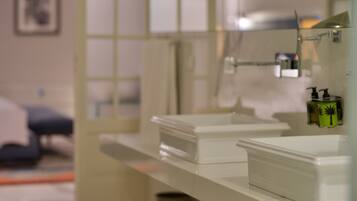 A bathroom with a white countertop, a mirror, and a shower area.