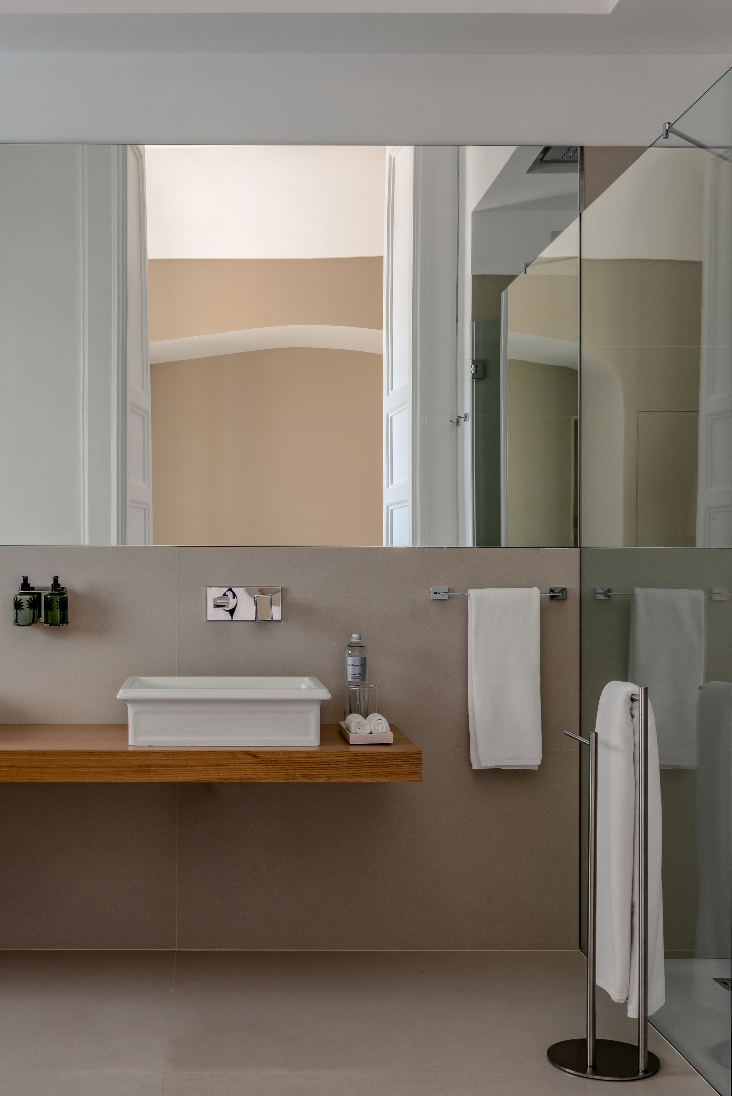 Een moderne badkamer met een houten wastafelmeubel, een douchecabine van glas en een handdoekrek.